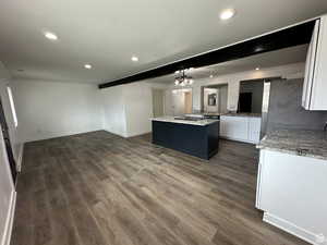 Kitchen featuring white cabinetry, light stone countertops, recessed lighting, open floor plan, and freestanding refrigerator