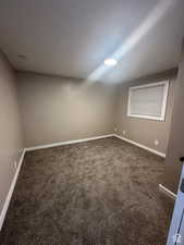 Unfurnished bedroom with dark carpet and baseboards