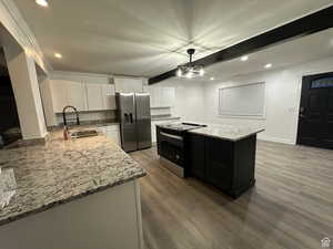 Kitchen featuring beamed ceiling, white cabinetry, light stone counters, stainless steel fridge with ice dispenser, and recessed lighting