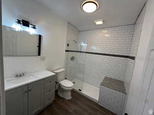 Bathroom with walk in shower, vanity, and dark wood-style flooring