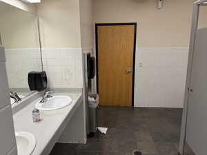 Full bath with tile walls, a wainscoted wall, and double vanity
