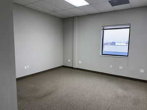 Empty room featuring a paneled ceiling and carpet
