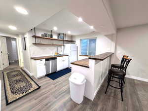 Kitchen/wetbar with a peninsula, open shelves, dark wood-style floors, and recessed lighting
