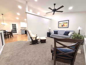 Living area featuring vaulted ceiling, light colored carpet, recessed lighting, a ceiling fan, and a chandelier