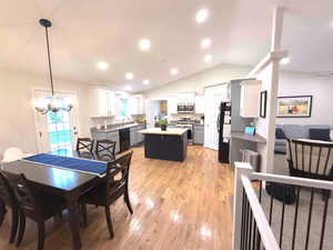 Dining space featuring vaulted ceiling, light wood-style flooring, recessed lighting, and a chandelier