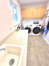 Washroom featuring cabinet space, light tile patterned floors, and washing machine and dryer