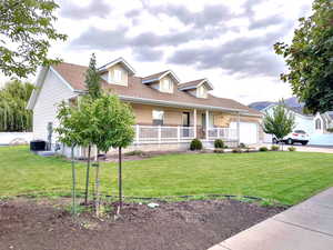 View of front of home featuring covered porch, a front lawn, a shingled roof, driveway, and an attached 2-car garage