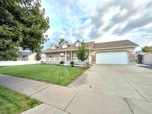 View of front facade with a porch, a front lawn, a 2 car garage, and driveway