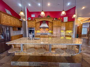 Kitchen with stainless steel appliances, light stone countertops, a breakfast bar area, recessed lighting, and high vaulted ceilinga hidden pantry behind the cabinets.