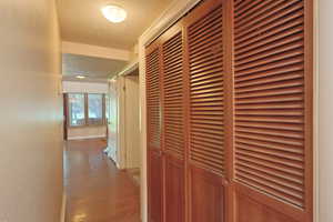 Corridor featuring a textured wall, wood finished floors, and a textured ceiling