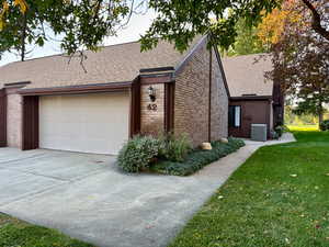View of front of house featuring roof with shingles, brick siding, a front yard, and stone siding