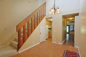 Stairs featuring wood finished floors, a chandelier, and a towering ceiling