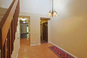 Empty room featuring light wood-style floors, stairway, and a chandelier