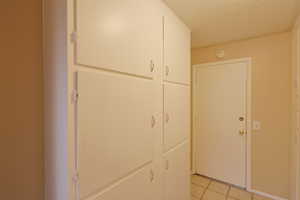 Hall featuring light tile patterned flooring and a textured ceiling