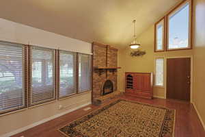Unfurnished living room featuring a fireplace, dark wood finished floors, high vaulted ceiling, and a textured ceiling