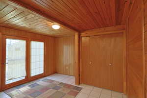 Unfurnished room featuring wood walls, light tile patterned floors, and wood ceiling