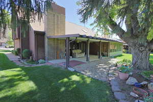 Back of property with a yard, a chimney, brick siding, a patio area, and a shingled roof