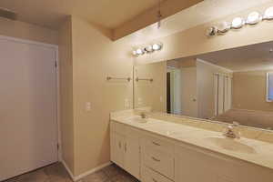 Bathroom featuring a textured ceiling, double vanity, and light tile patterned floors