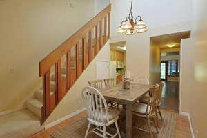 Virtually staged dining area featuring stairway, light wood-style flooring, and a chandelier