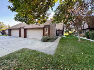 View of front facade with brick siding, a front yard, concrete driveway, roof with shingles, and an attached garage