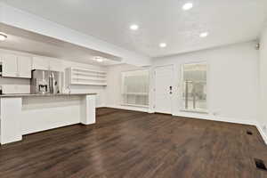 Kitchen with white cabinets, dark wood finished floors, stainless steel fridge with ice dispenser, a textured ceiling, and recessed lighting