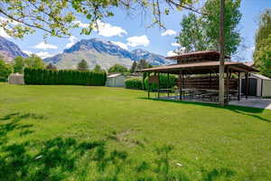View of grassy yard with a storage shed, a gazebo, a mountain view, and a patio area