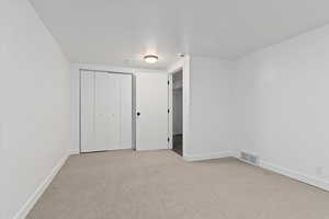 Unfurnished bedroom featuring light colored carpet and a closet