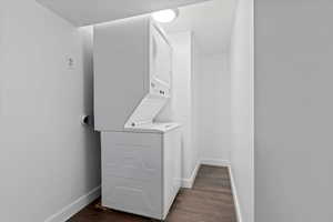 Laundry area with stacked washer and clothes dryer and dark wood-style floors