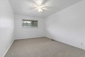 Carpeted empty room with brick wall and ceiling fan