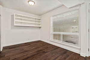 Spare room with dark wood-style floors, crown molding, and a textured ceiling
