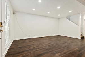 Below grade area with dark wood-style floors, recessed lighting, stairway, and brick wall