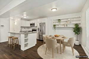 Kitchen featuring open shelves, stainless steel appliances, white cabinets, an island with sink, and dark wood-type flooring