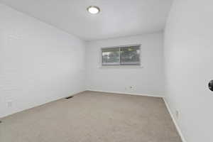 Unfurnished room with carpet flooring and brick wall