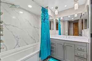 Bathroom with a combined bath / shower with marble appearance, vanity, and recessed lighting