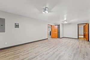 Empty room with light wood-type flooring and electric panel