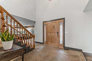 Entryway featuring stone tile floors, stairs, and a towering ceiling