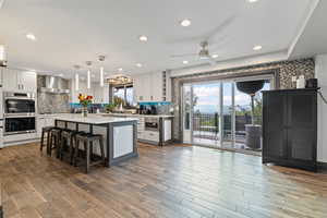 Kitchen featuring pendant lighting, a breakfast bar, backsplash, stainless steel appliances, and light stone counters