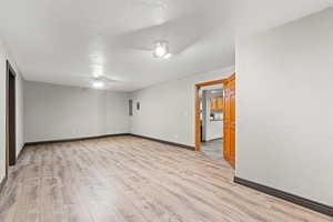 Unfurnished room with light wood-style floors, a textured ceiling, and a textured wall