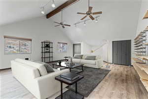 Great Room over the garage.  Living area featuring track lighting, high vaulted ceiling, beamed ceiling, light wood-style flooring, and ceiling fan