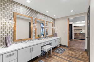 Bathroom with double vanity and dark wood-style floors