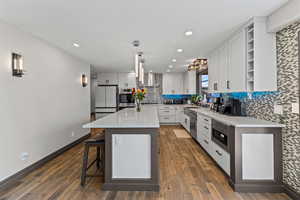 Kitchen featuring a kitchen breakfast bar, light stone countertops, open shelves, a kitchen island, and tasteful backsplash