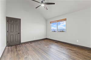 Empty room featuring high vaulted ceiling, dark wood finished floors, and ceiling fan