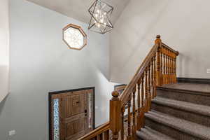 Entryway featuring a towering ceiling, a chandelier, and stairway