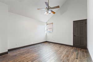 Empty room with high vaulted ceiling, dark wood-style flooring, and ceiling fan