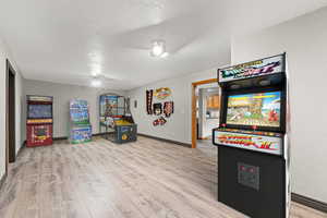 Recreation room featuring light wood-style flooring and a textured ceiling. Virtually staged