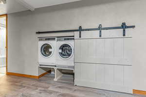 Laundry room featuring a barn door, light wood-style floors, and washer and dryer