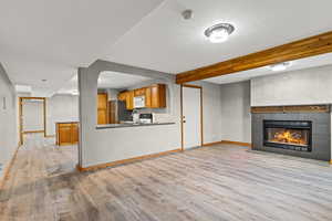 Unfurnished living room with beam ceiling, light wood finished floors, and a fireplace