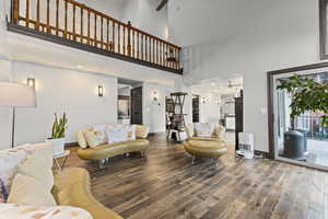Living room featuring a ceiling fan, plenty of natural light, a towering ceiling, and wood finished floors