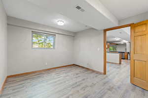 Spare room featuring light wood-style flooring and baseboards