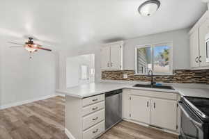 Kitchen with light countertops, a peninsula, white cabinets, stainless steel appliances, and light wood-style flooring